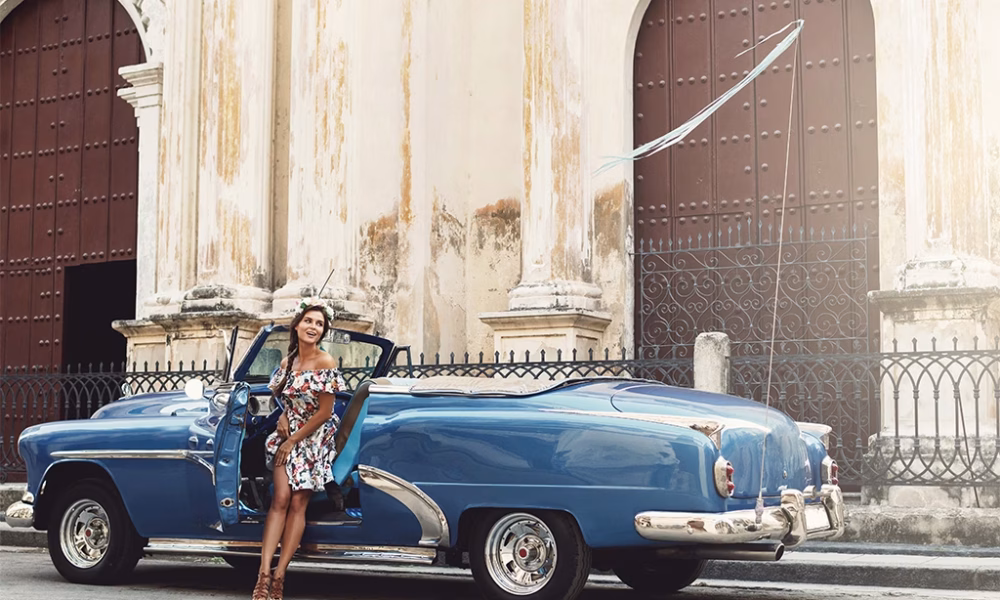 Woman wearing beautiful dress and retro convertible car at Havana city